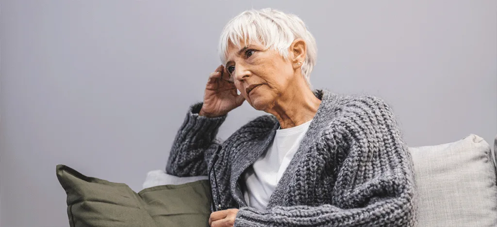 Older adult wearing a hearing aid and smiling